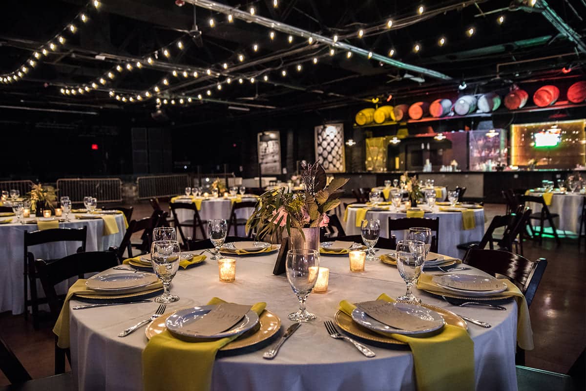 Modern reception setup with bistro string lighting, yellow accents, and elegant table settings by Michaelis Events – Top Event Planners in Louisville KY & Best Wedding Caterers.