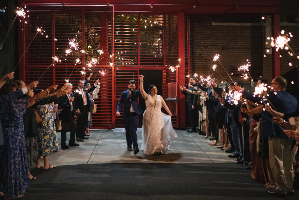 Bride and groom make a joyful sparkler exit surrounded by guests at their Louisville wedding at Frazier History Museum, coordinated by Michaelis Events and photographed by Sarah Katherine Davis.